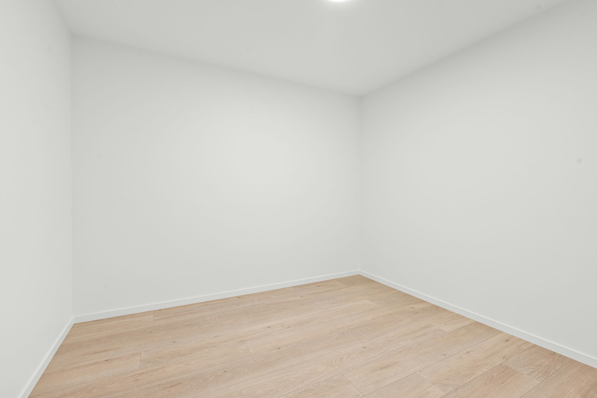An empty room with a wood floor and white walls